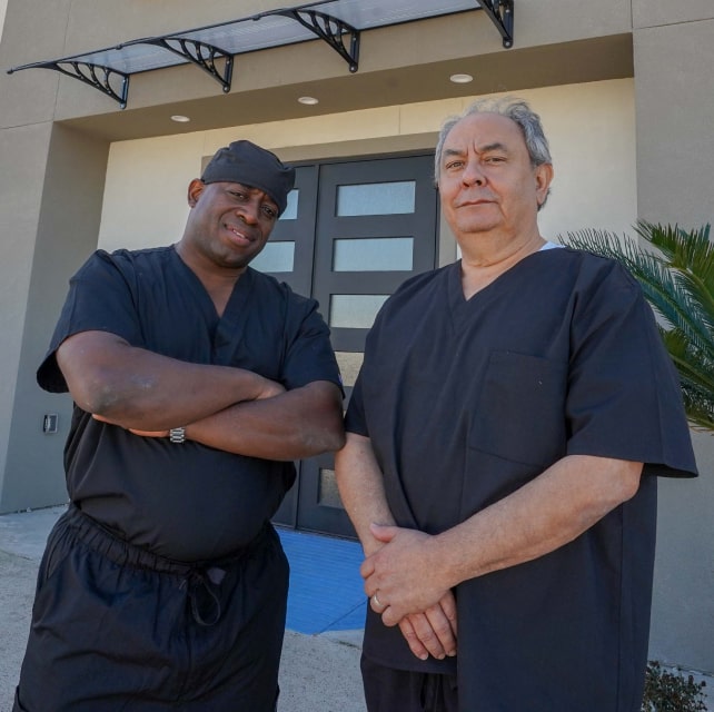 Dr. Collins with one of his assistants at the entrance of the Manvel TX dental office smiling