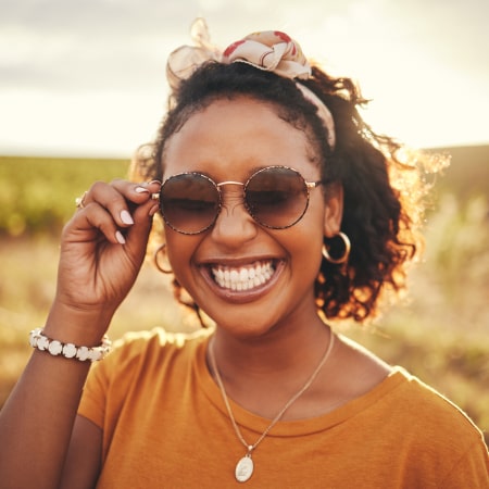 A woman with glasses showing off her beautiful smile