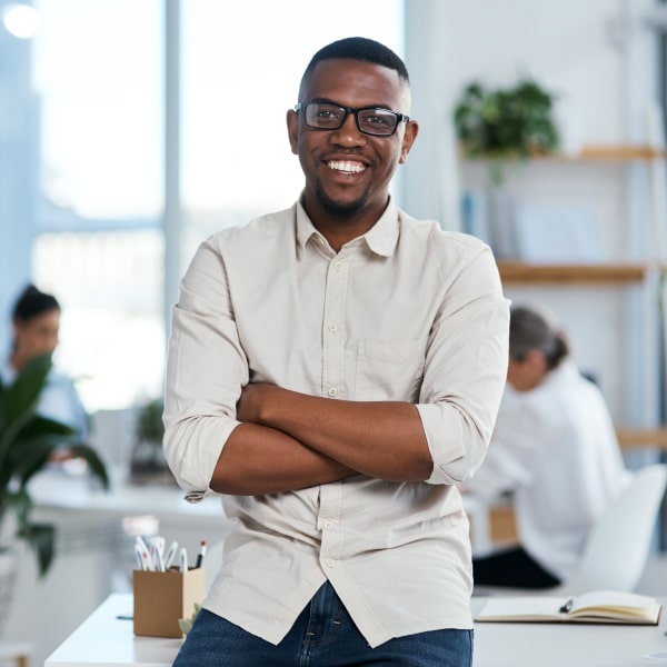 Young man in office smiling while crossing his arms